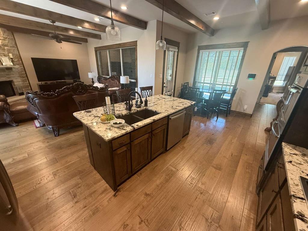 125 Lucky Ridge Lane Boyd, TX 76023 - Photo 19 of 29 Kitchen featuring hardwood / wood-style floors, beamed ceiling, ceiling fan, arched walkways, and light stone counters