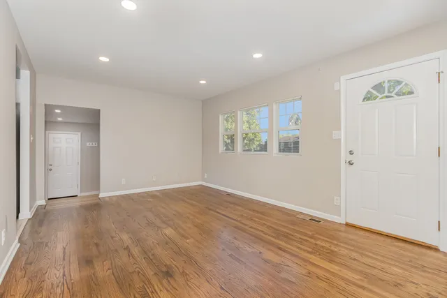 a view of an empty room with wooden floor and a window