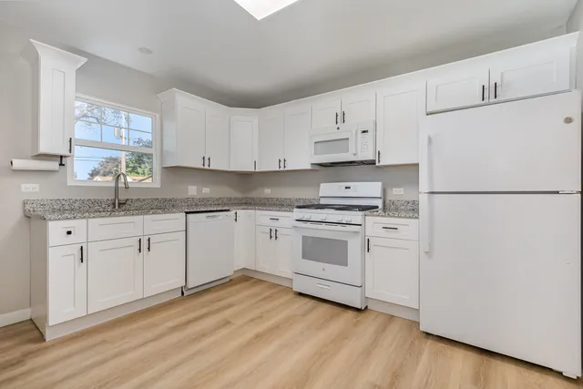 a kitchen with granite countertop white cabinets and white appliances