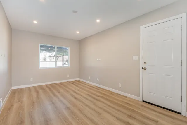 a view of an empty room with wooden floor and a window