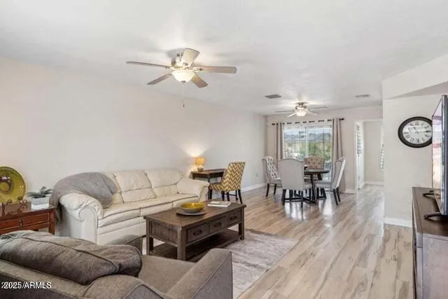 a living room with furniture a chandelier fan and a window