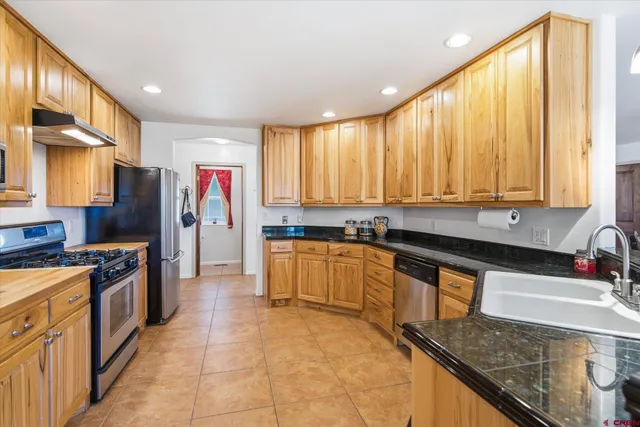 a large kitchen with stainless steel appliances granite countertop a stove a sink and a refrigerator