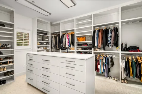 a view of walk in closet with clothes and shoes