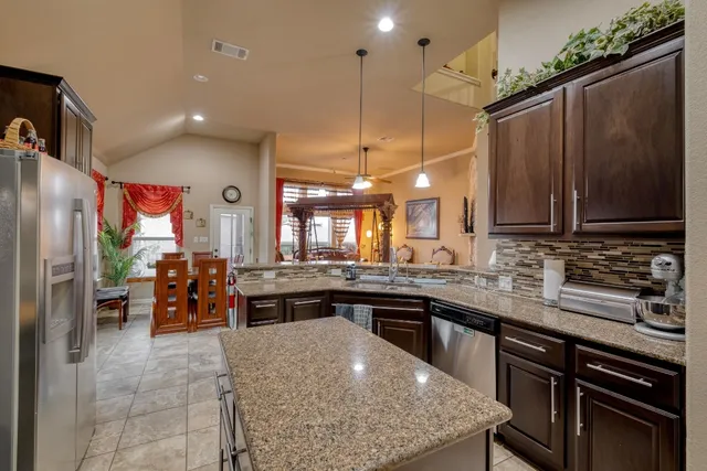 a kitchen with stainless steel appliances granite countertop a sink a stove and a refrigerator