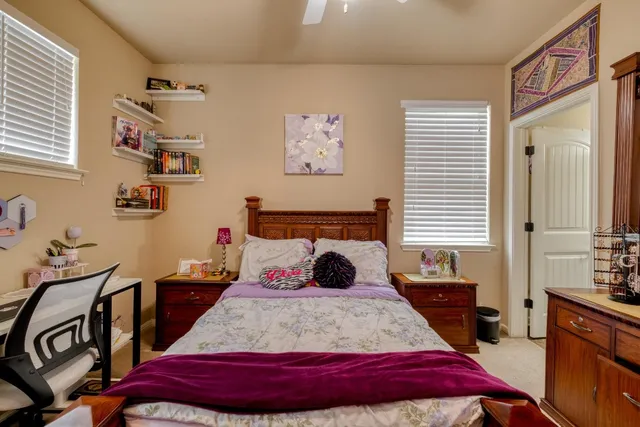 a bedroom with a bed a dresser and next to a window