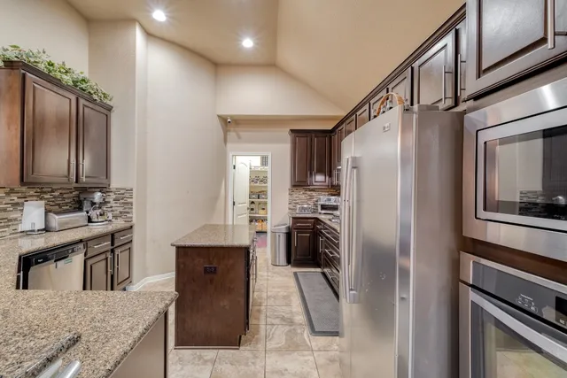 a kitchen with stainless steel appliances granite countertop a refrigerator a oven and a sink