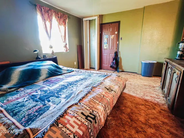 a bedroom with a bed chair and dresser