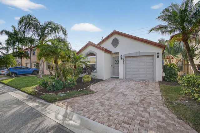 a view of a house with a yard and palm trees