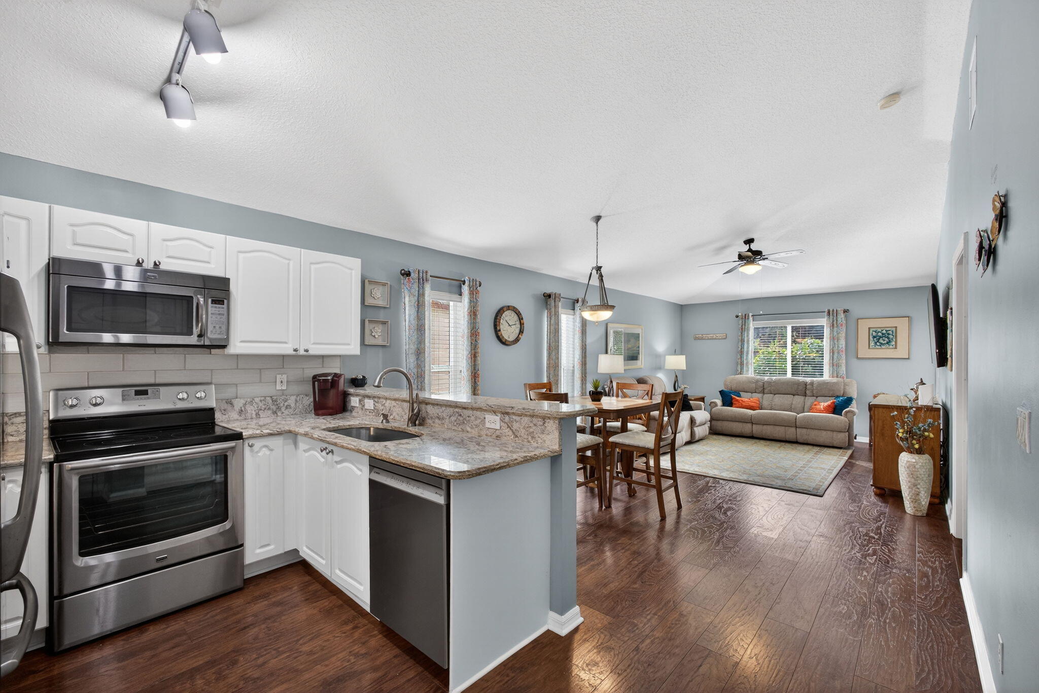 1095 Via Jardin Riviera Beach, FL 33418 - Photo 7 of 44 a open kitchen with stainless steel appliances granite countertop a stove top oven a refrigerator a dining table and chairs with wooden floor