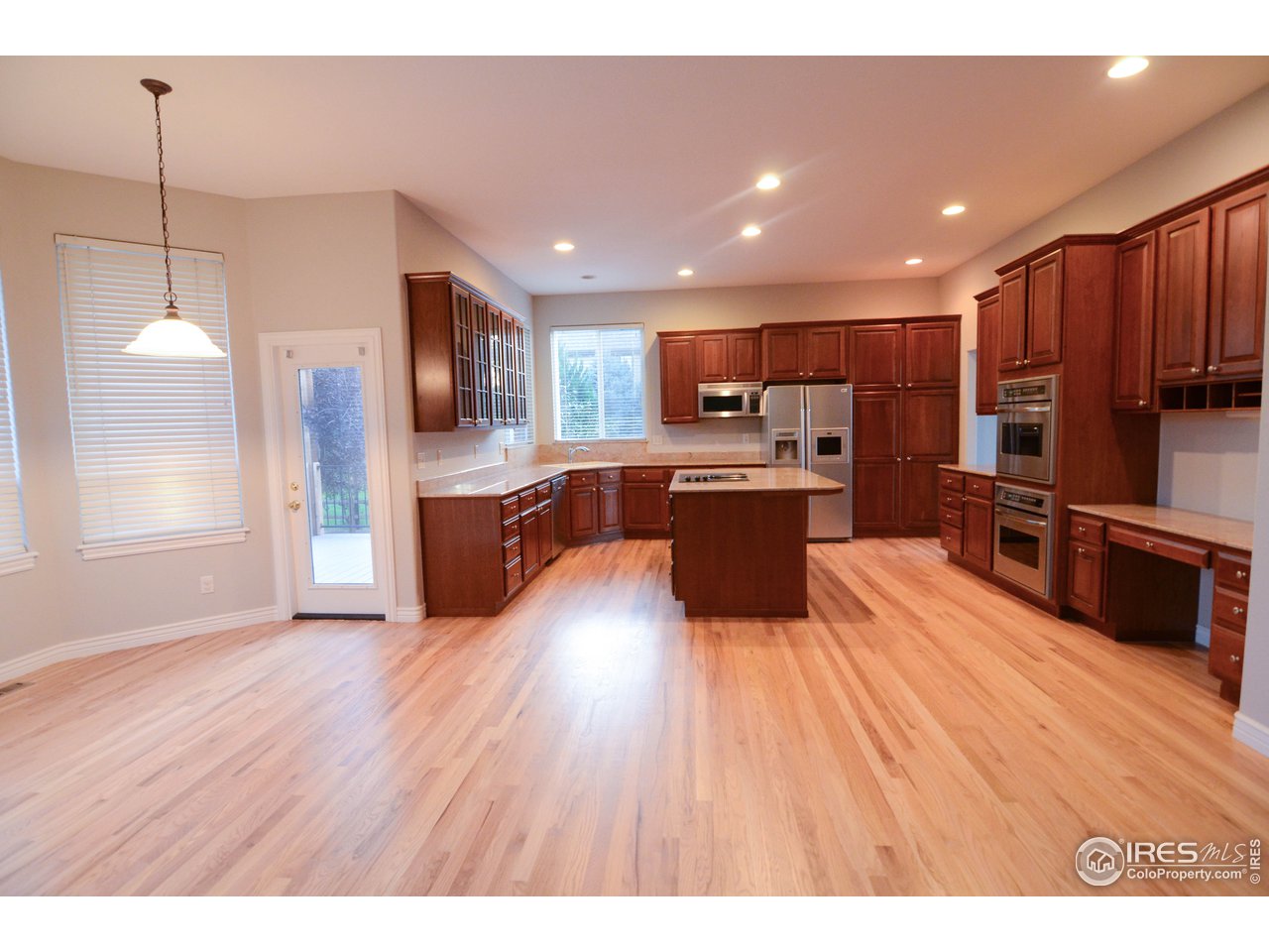 1797 Ridge W Drive Windsor, CO 80550 - Photo 8 of 33 a kitchen with stainless steel appliances wooden floors and wooden cabinets