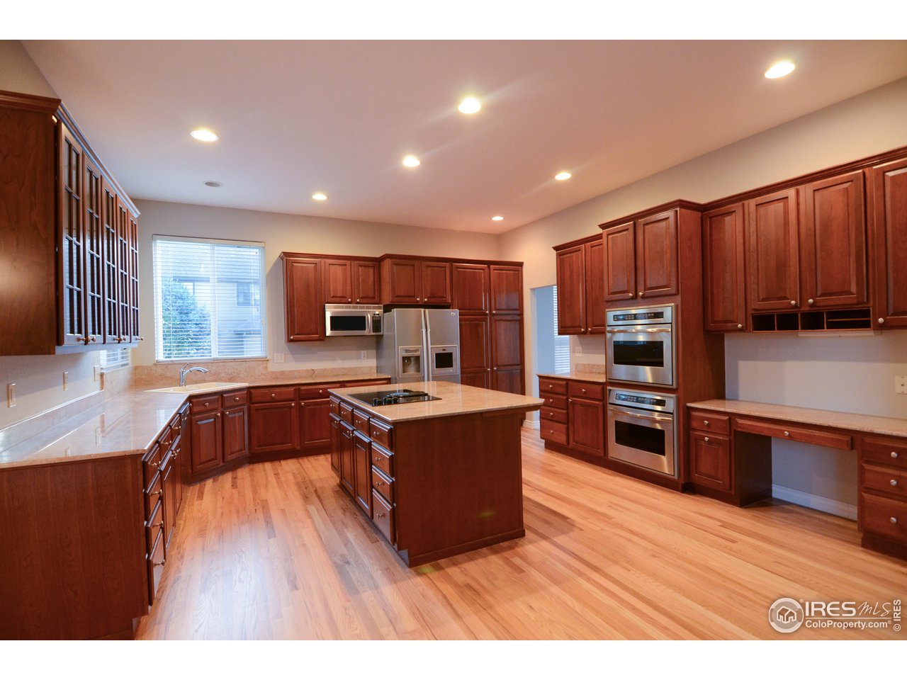 1797 Ridge W Drive Windsor, CO 80550 - Photo 10 of 33 a kitchen with stainless steel appliances granite countertop a stove a refrigerator a sink a oven with wooden cabinets and wooden floor