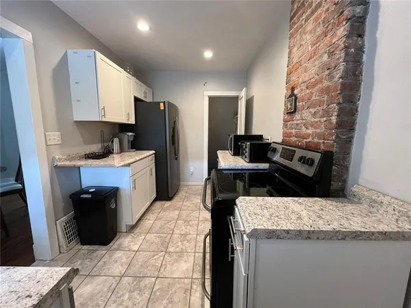a kitchen with granite countertop a sink a stove and refrigerator