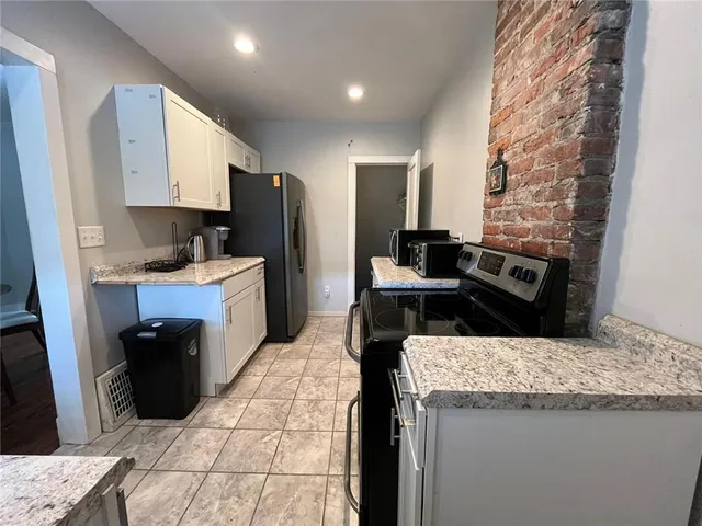 a kitchen with granite countertop a sink a stove and refrigerator