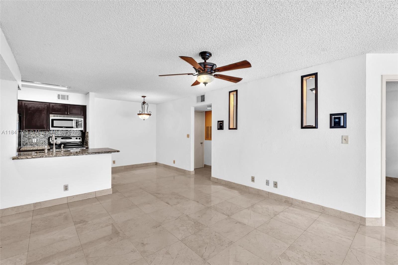 2796 South University Drive, Unit 2104 Davie, FL 33328 - Photo 14 of 41 a view of a kitchen with flat screen tv and a ceiling fan
