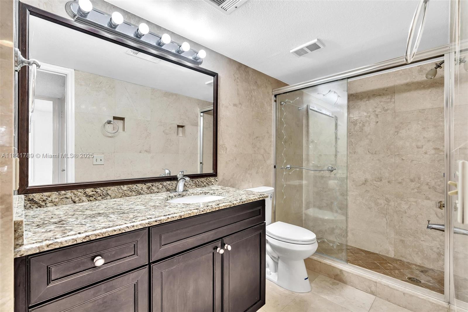 2796 South University Drive, Unit 2104 Davie, FL 33328 - Photo 23 of 41 a bathroom with a granite countertop sink toilet a mirror and shower
