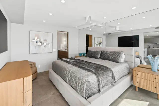 a spacious bedroom with a bed and a flat screen tv