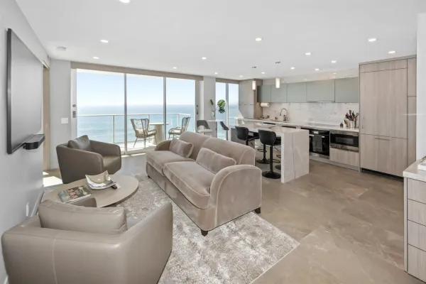 a living room with furniture kitchen view and a large window