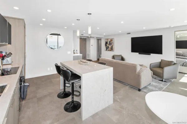 a living room with furniture a flat screen tv and kitchen view