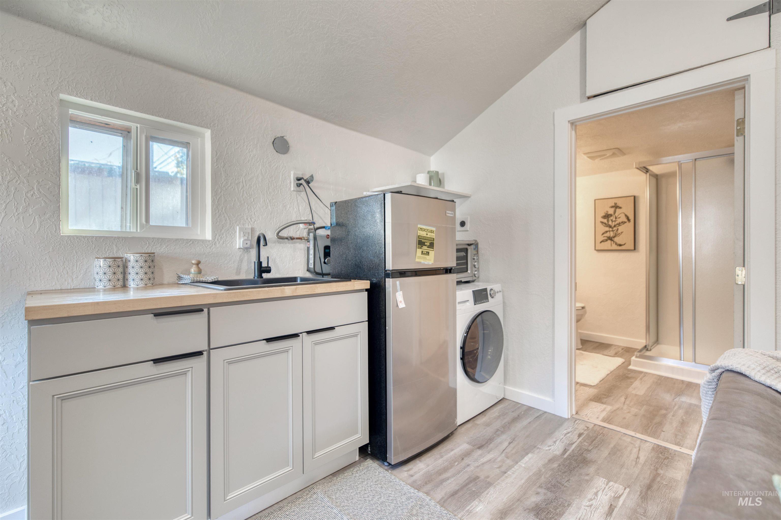3311 West Hamilton Street Boise, ID 83705 - Photo 26 of 32 Laundry room featuring washer / dryer, a textured wall, light wood-style floors, and vaulted ceiling