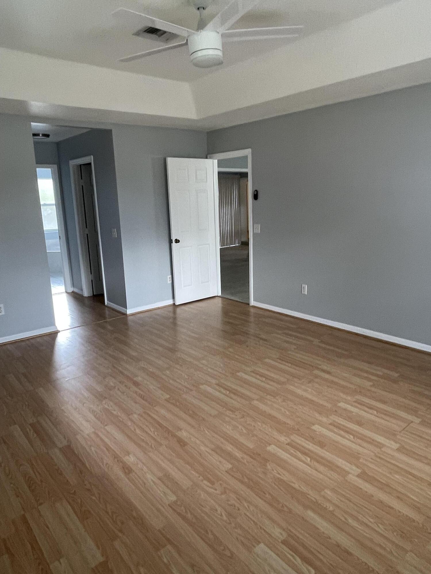 145 Southwest Hawthorne Circle Port St. Lucie, FL 34953 - Photo 14 of 37 a view of an empty room with wooden floor and a ceiling fan