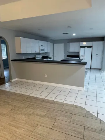 a view of kitchen with kitchen island microwave and cabinets
