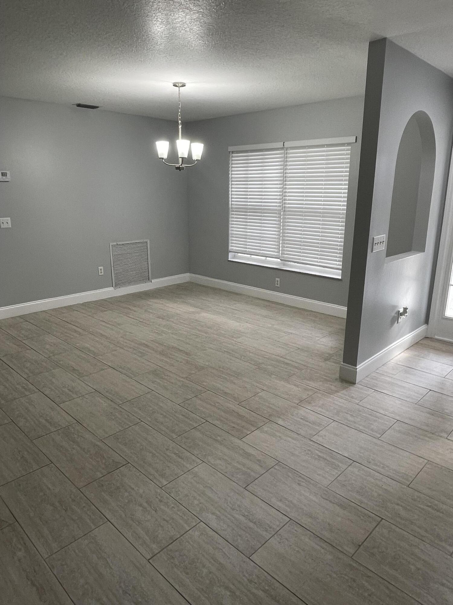 145 Southwest Hawthorne Circle Port St. Lucie, FL 34953 - Photo 21 of 37 an empty room with wooden floor and windows