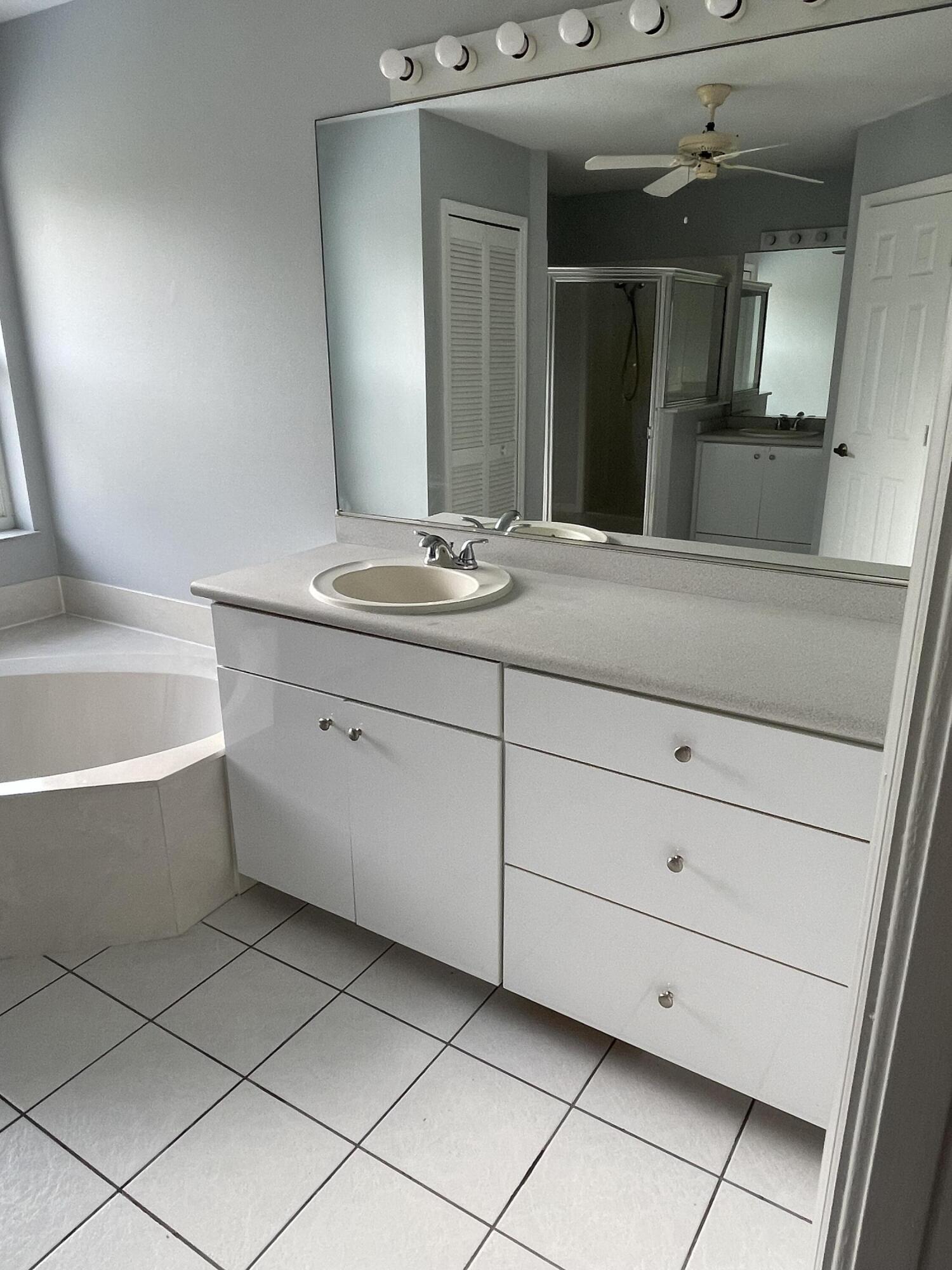145 Southwest Hawthorne Circle Port St. Lucie, FL 34953 - Photo 27 of 37 a bathroom with a bathtub sink and mirror