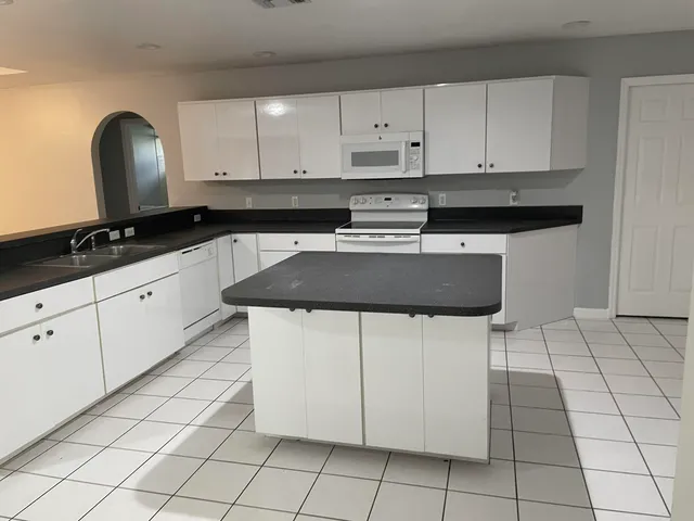 a kitchen with granite countertop white cabinets and sink
