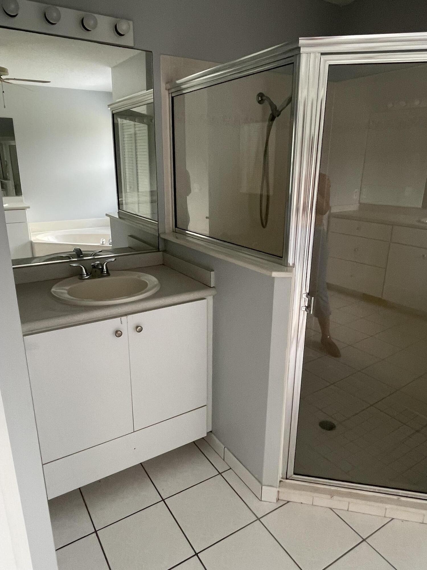 145 Southwest Hawthorne Circle Port St. Lucie, FL 34953 - Photo 6 of 37 a bathroom with a granite countertop sink a mirror and shower