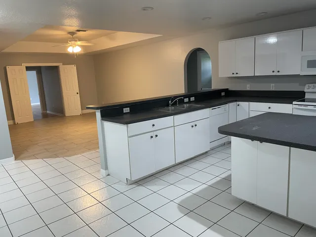 a kitchen with granite countertop white cabinets and a sink