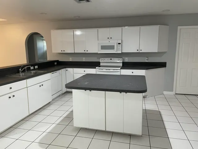 a kitchen with granite countertop white cabinets and white appliances