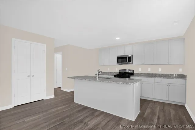 a kitchen with granite countertop a sink stove and microwave