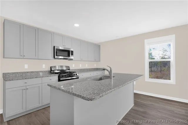 a kitchen with granite countertop a sink a stove and cabinets
