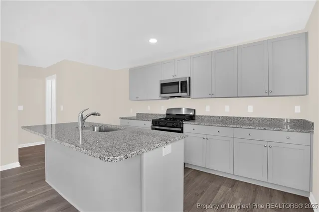 a kitchen with kitchen island granite countertop a sink a stove and cabinets
