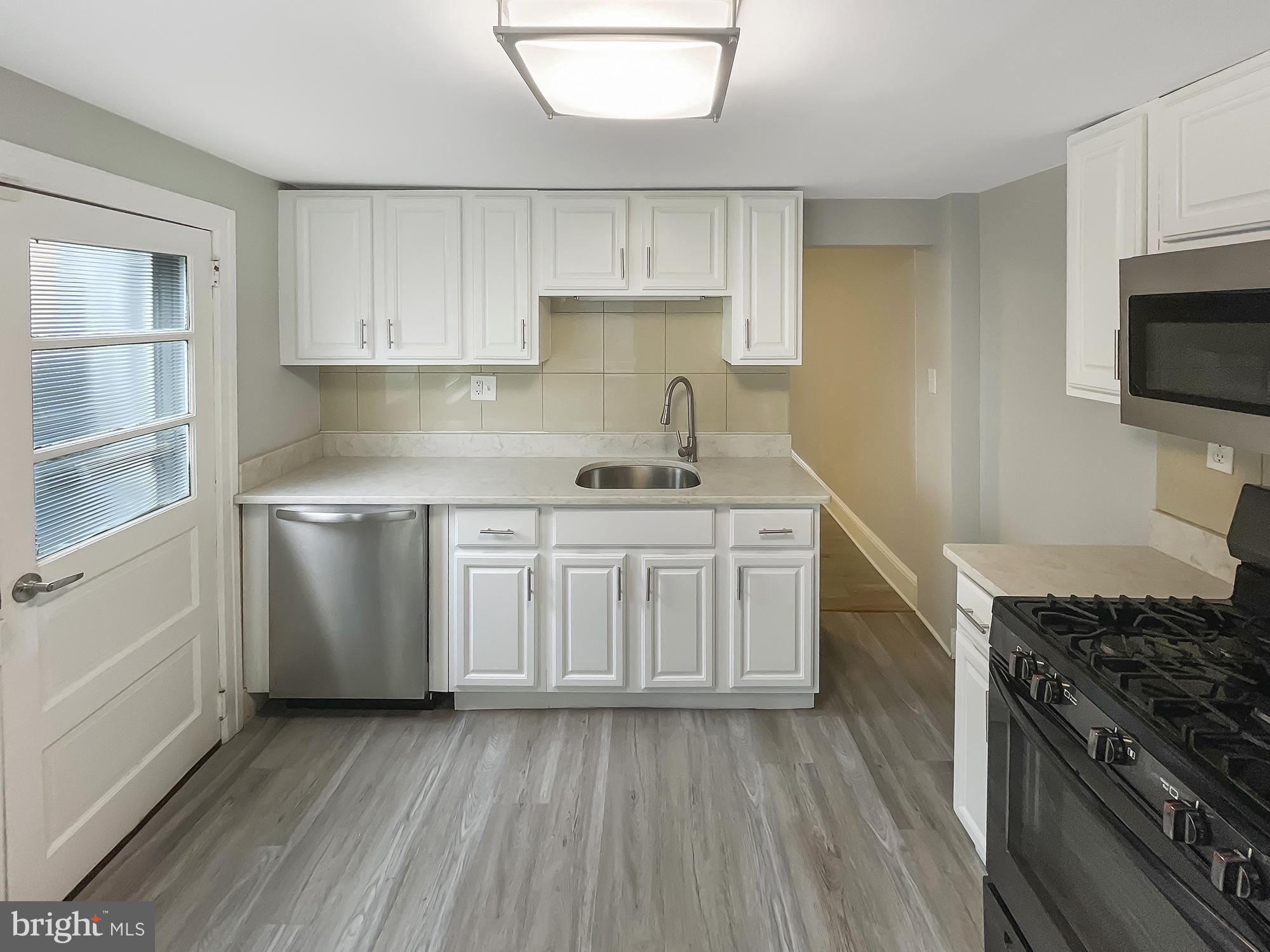 160 McClellan Street Philadelphia, PA 19148 - Photo 7 of 29 a kitchen with white cabinets stainless steel appliances and sink