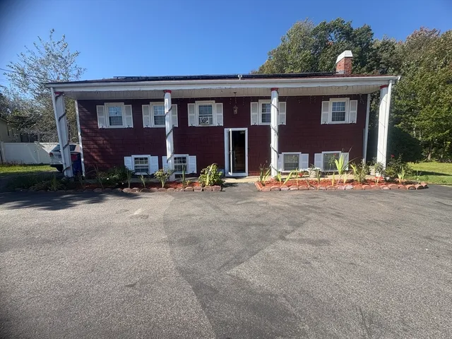a front view of a house with lots of trees and plants