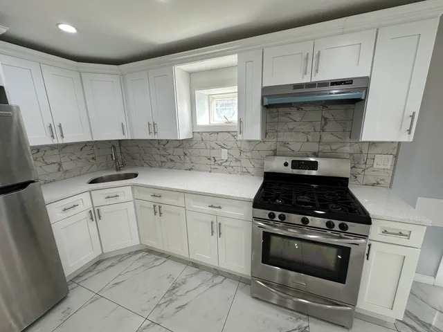a kitchen with white cabinets and appliances