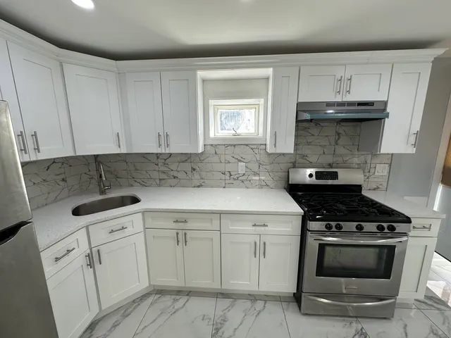 a kitchen with white cabinets and appliances