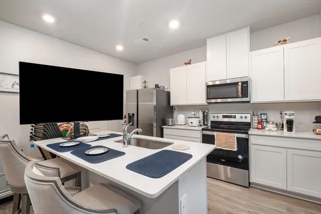 a kitchen with stainless steel appliances a stove a sink a microwave a refrigerator and cabinets