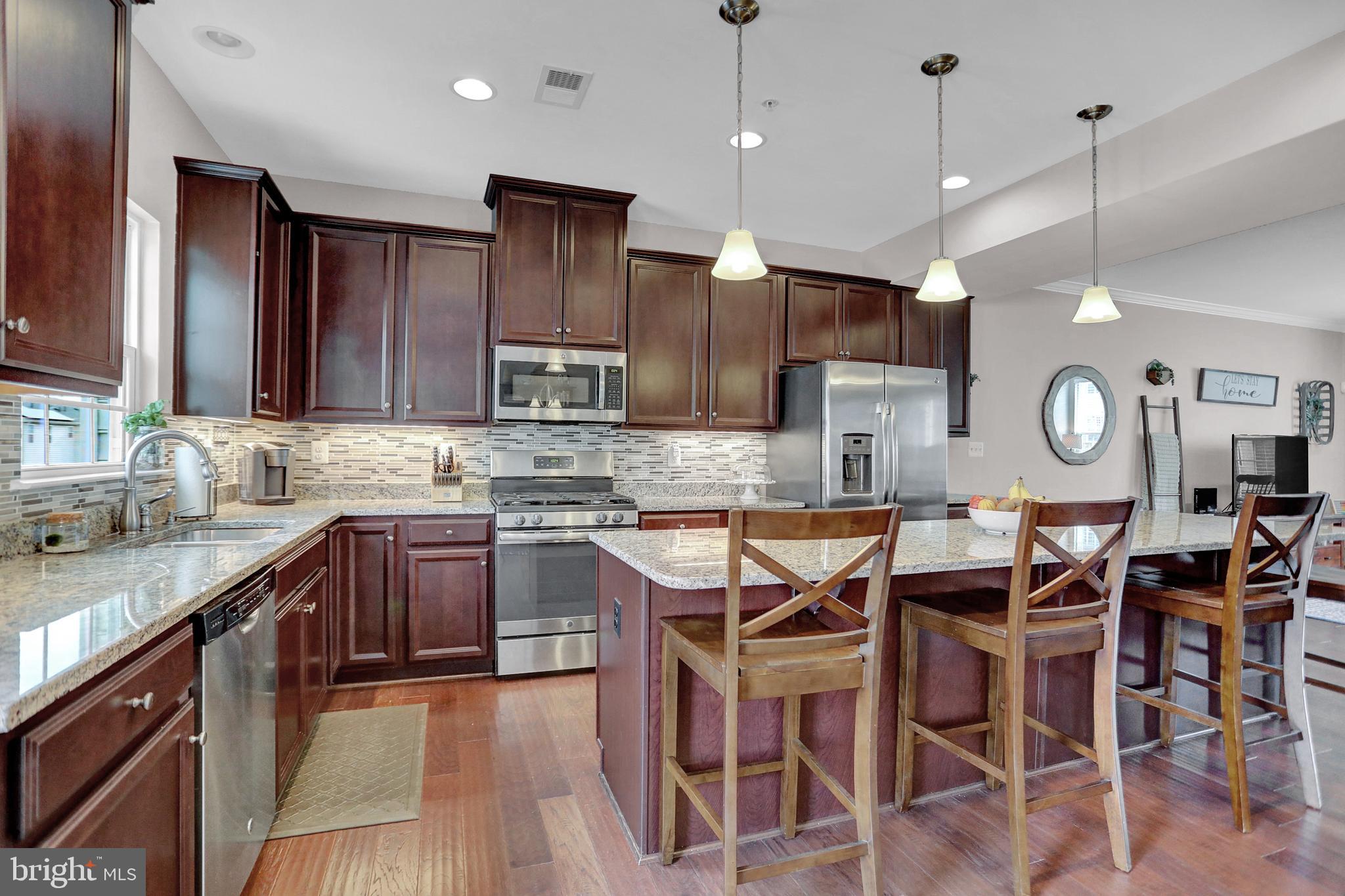 a kitchen with stainless steel appliances kitchen island granite countertop a sink a stove a dining table and chairs