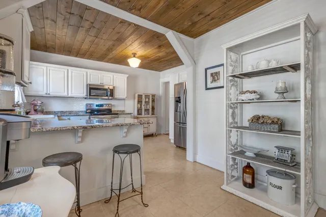 a kitchen with stainless steel appliances granite countertop a refrigerator a sink a stove and white cabinets with wooden floor