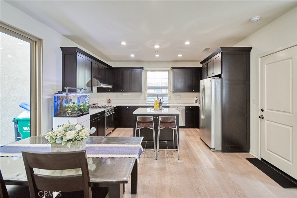 129 Excursion Irvine, CA 92618 - Photo 12 of 53 a kitchen with kitchen island a refrigerator and a dining table