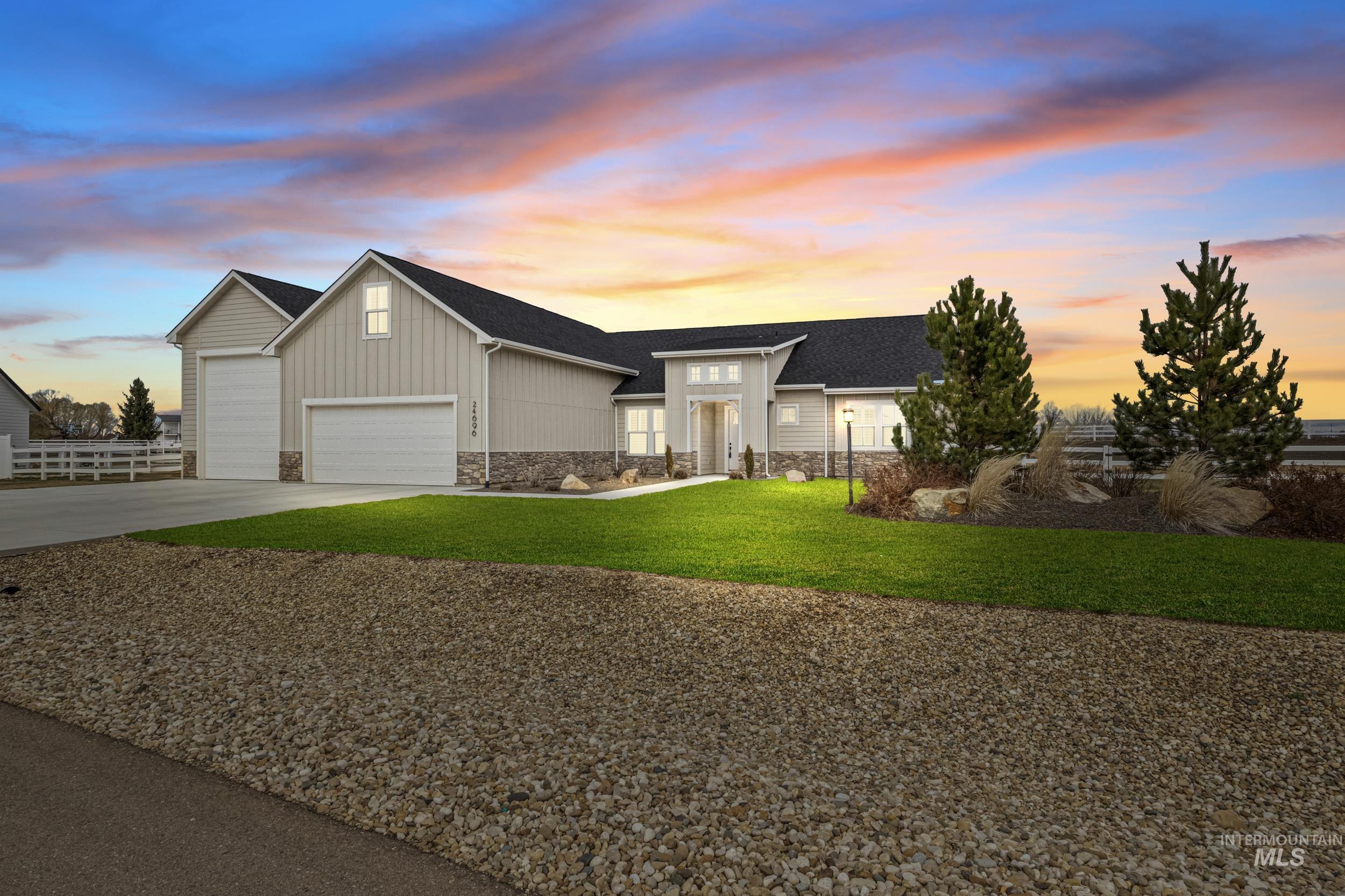 View of front of property featuring a lawn, stone siding, concrete driveway, board and batten siding, and a garage