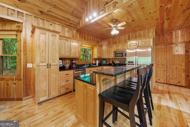 a kitchen with stainless steel appliances granite countertop a stove a refrigerator a sink dishwasher a dining table and chairs with wooden floor