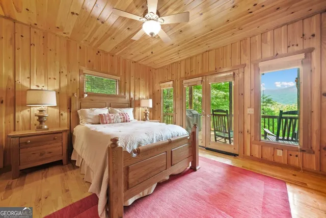 a spacious bedroom with a balcony a bed and a dresser next to a window