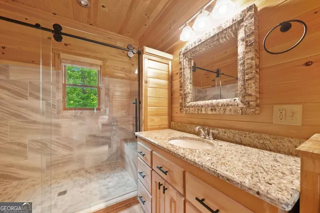 a bathroom with a granite countertop sink a mirror and a shower