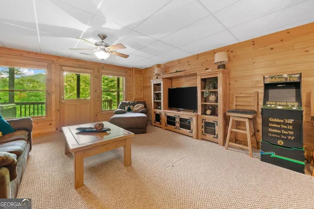 a living room with furniture a flat screen tv and floor to ceiling window