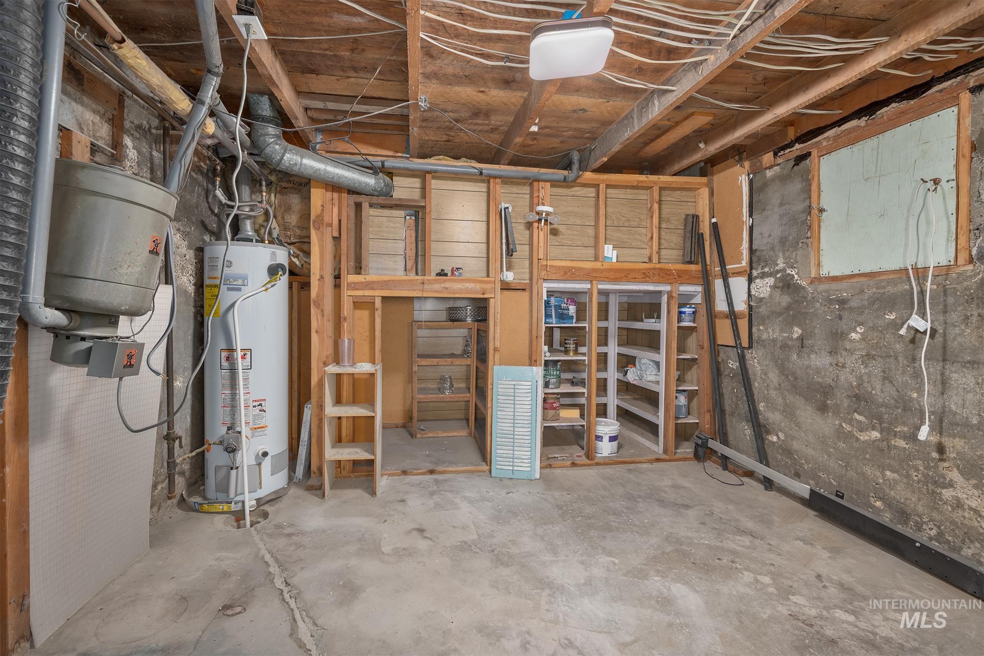 61 Southwest 4th Street Ontario, OR 97914 - Photo 27 of 42 Utility space featuring a water heater, exposed concrete flooring, open wood framing, built-in shelving, and exposed ceiling joists
