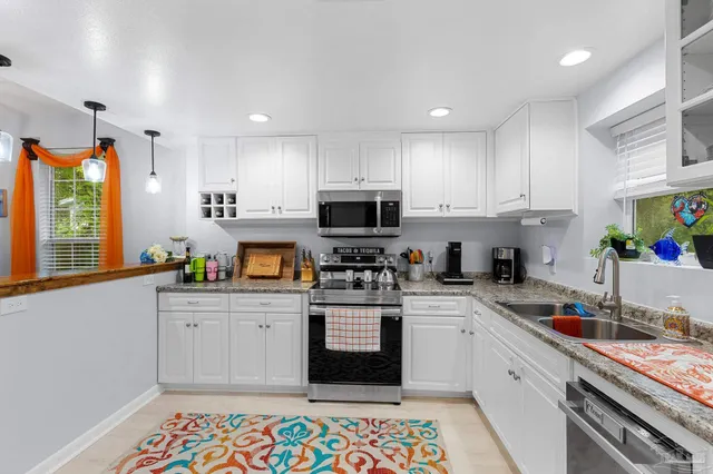 a kitchen with granite countertop a sink stainless steel appliances and cabinets