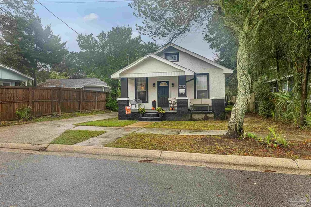 a view of a house with a yard and large tree